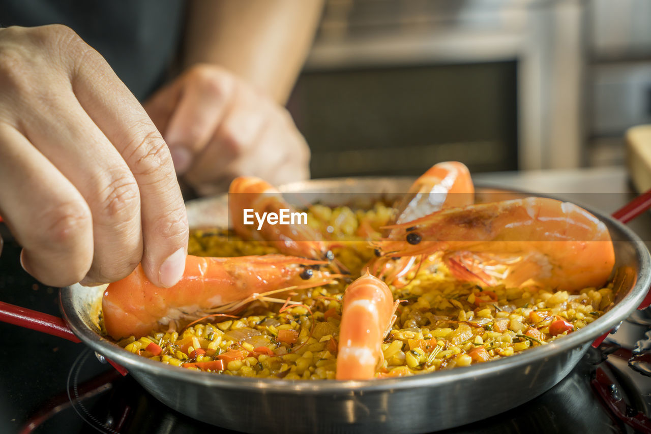 Cropped image of chef arranging shrimp on paella in container