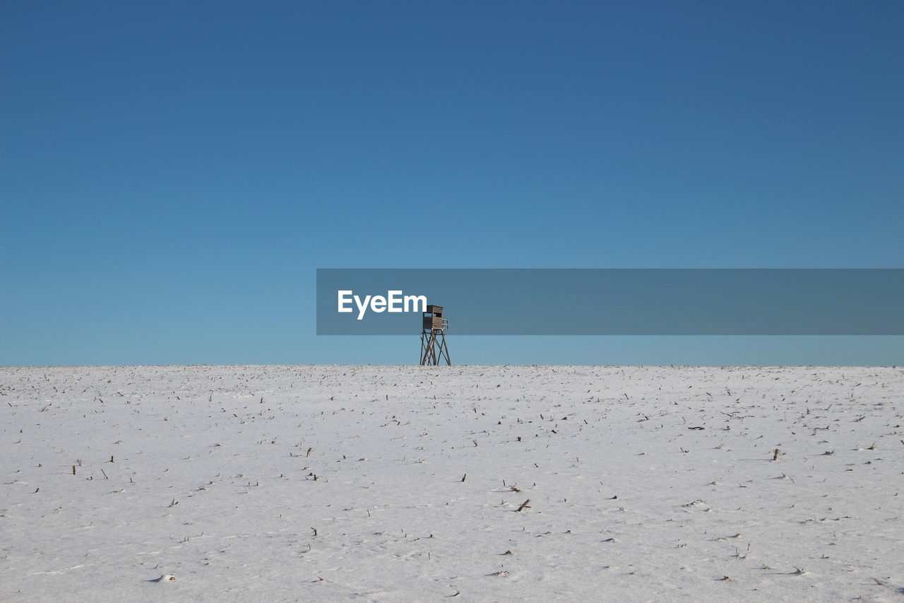 MAN STANDING ON SAND AGAINST CLEAR SKY