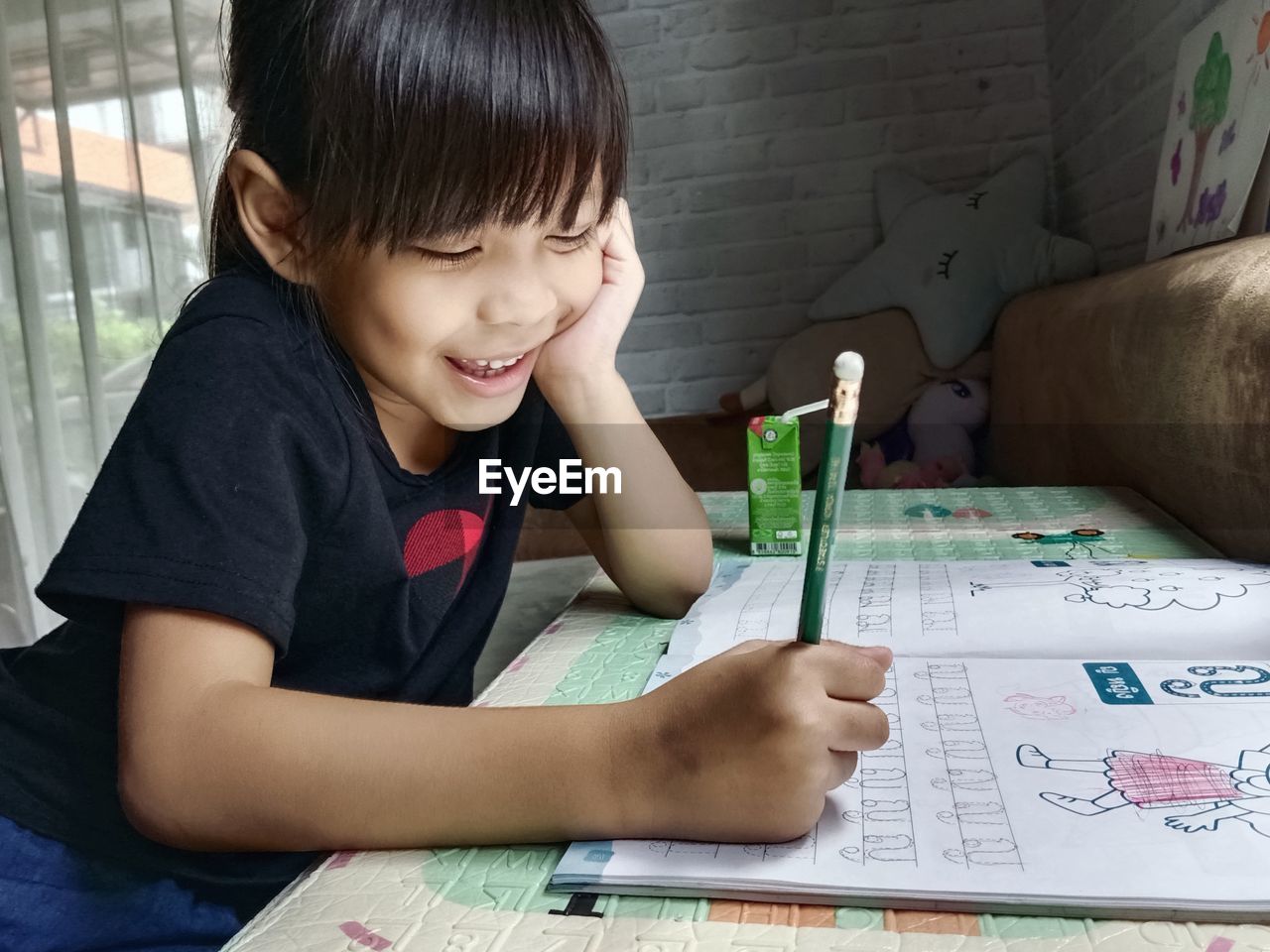 Girl drawing on book at home