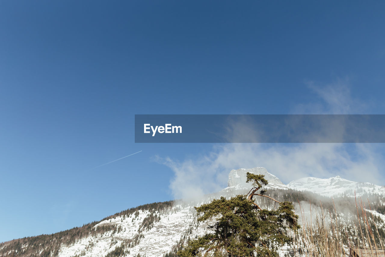 Low angle view of snowcapped mountain against blue sky