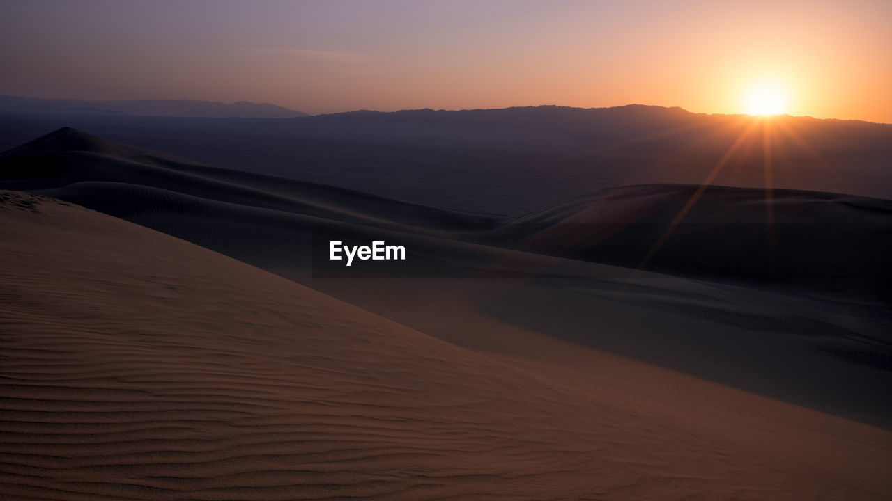 SCENIC VIEW OF DESERT AGAINST SKY AT SUNSET