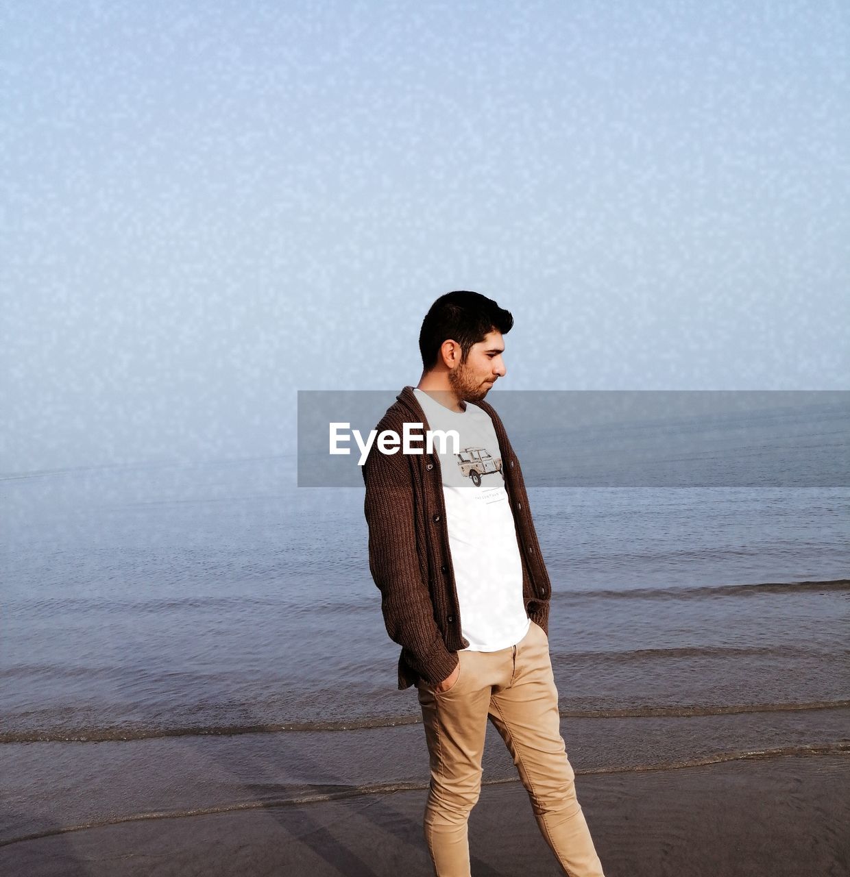 Young man standing on beach against sky