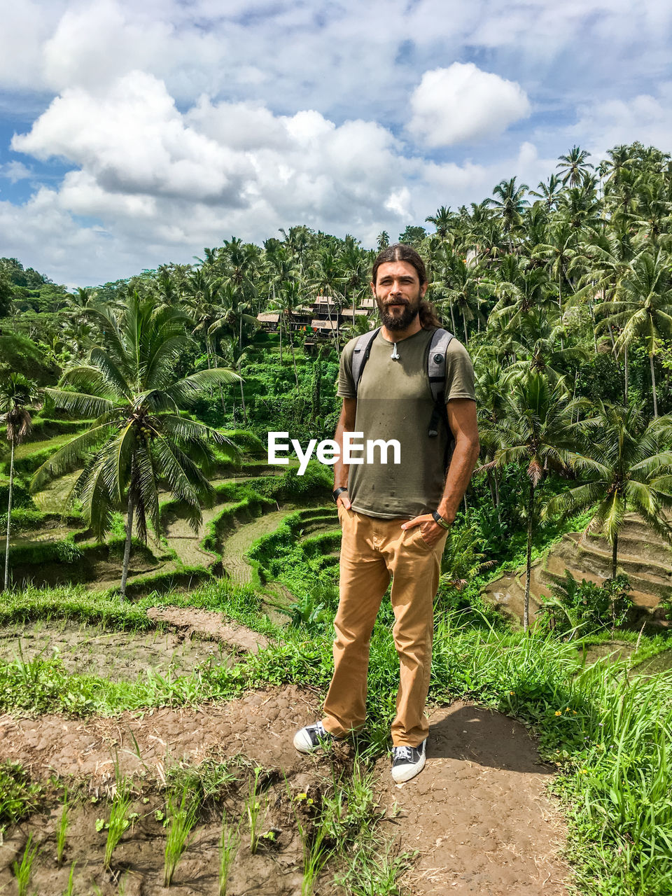 Portrait of man standing on land against palm trees