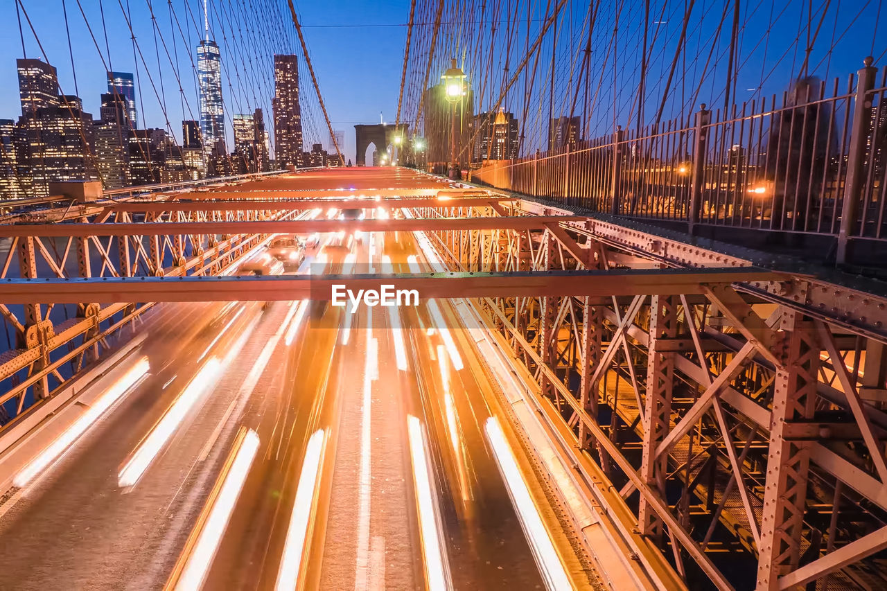 Blurred motion of cars on brooklyn bridge in city at night