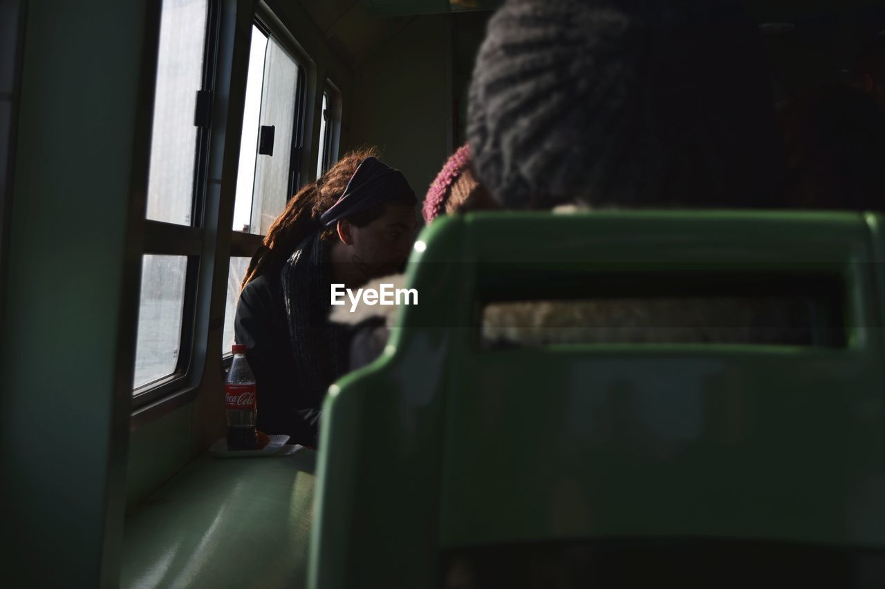 REAR VIEW OF PEOPLE SITTING ON TRAIN