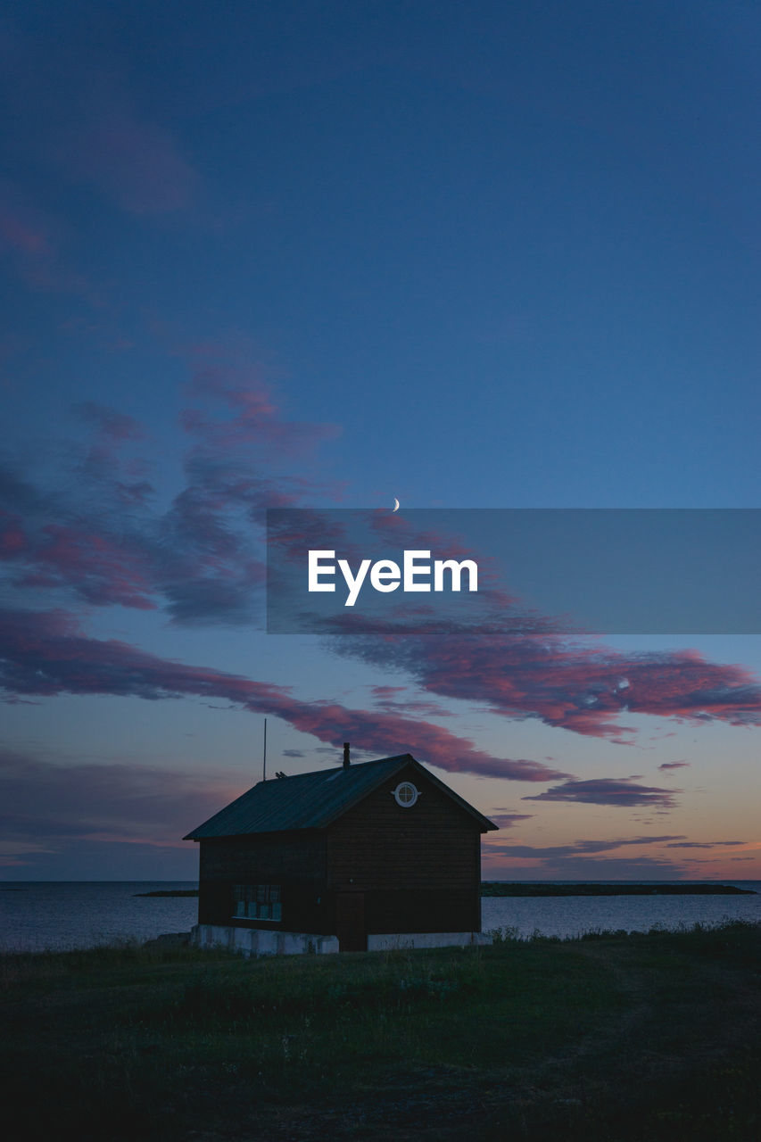 HOUSES BY SEA AGAINST SKY AT SUNSET