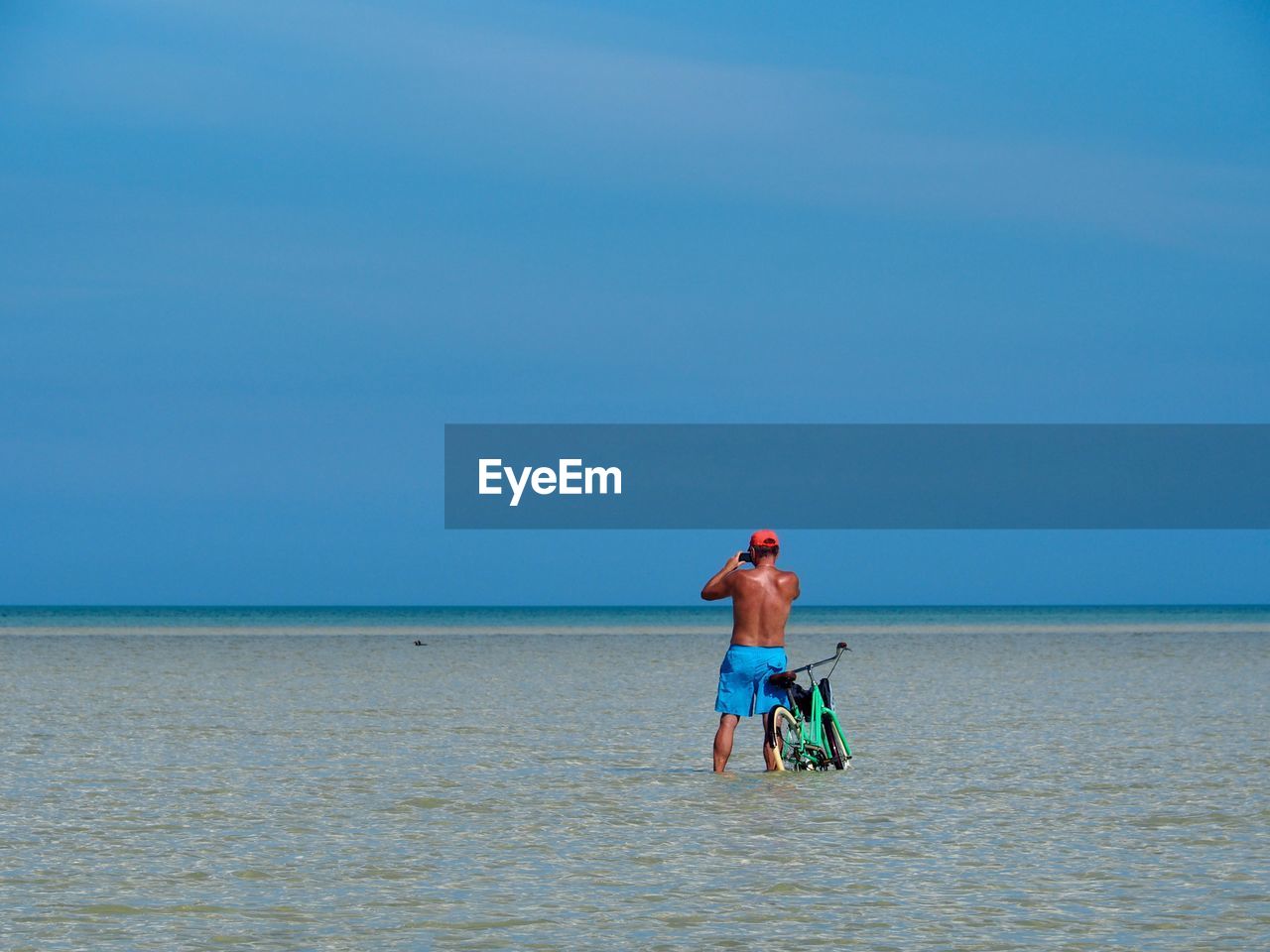 FULL LENGTH REAR VIEW OF MAN ON BEACH AGAINST SKY