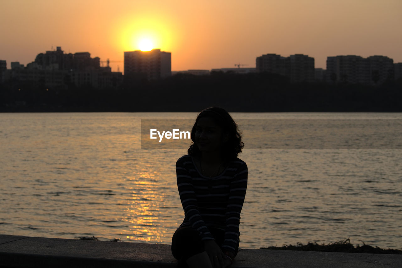 REAR VIEW OF WOMAN STANDING ON SEA