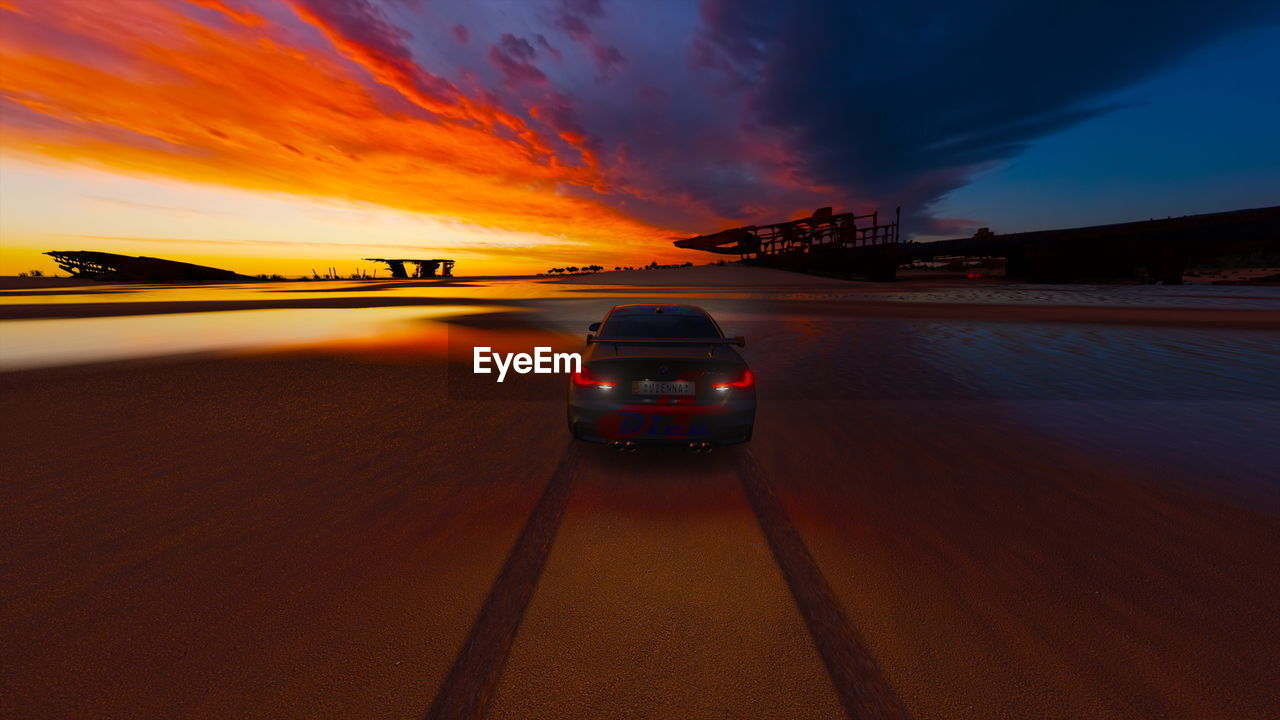 CAR ON ROAD AGAINST SKY AT SUNSET