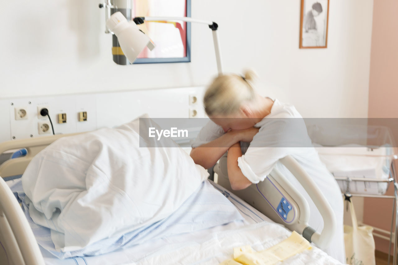 Mid adult woman leaning against hospital bed