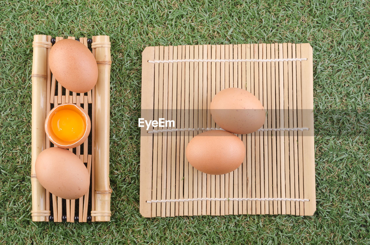 Directly above shot of egg in spoon on bamboo mat over grass