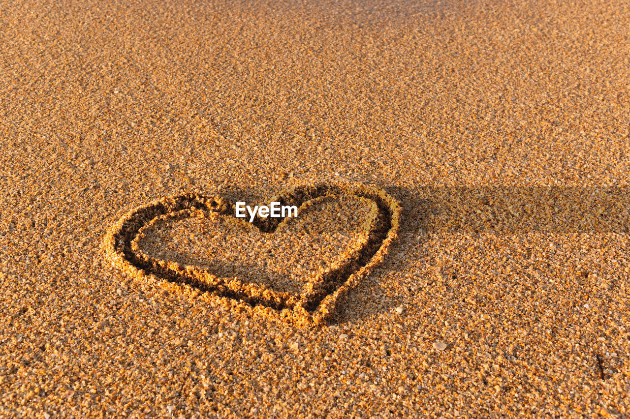 Heart drawn in the sand. beach background. top view