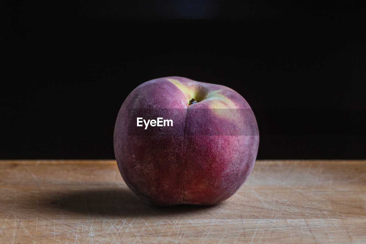 A peach on a kitchen wooden board