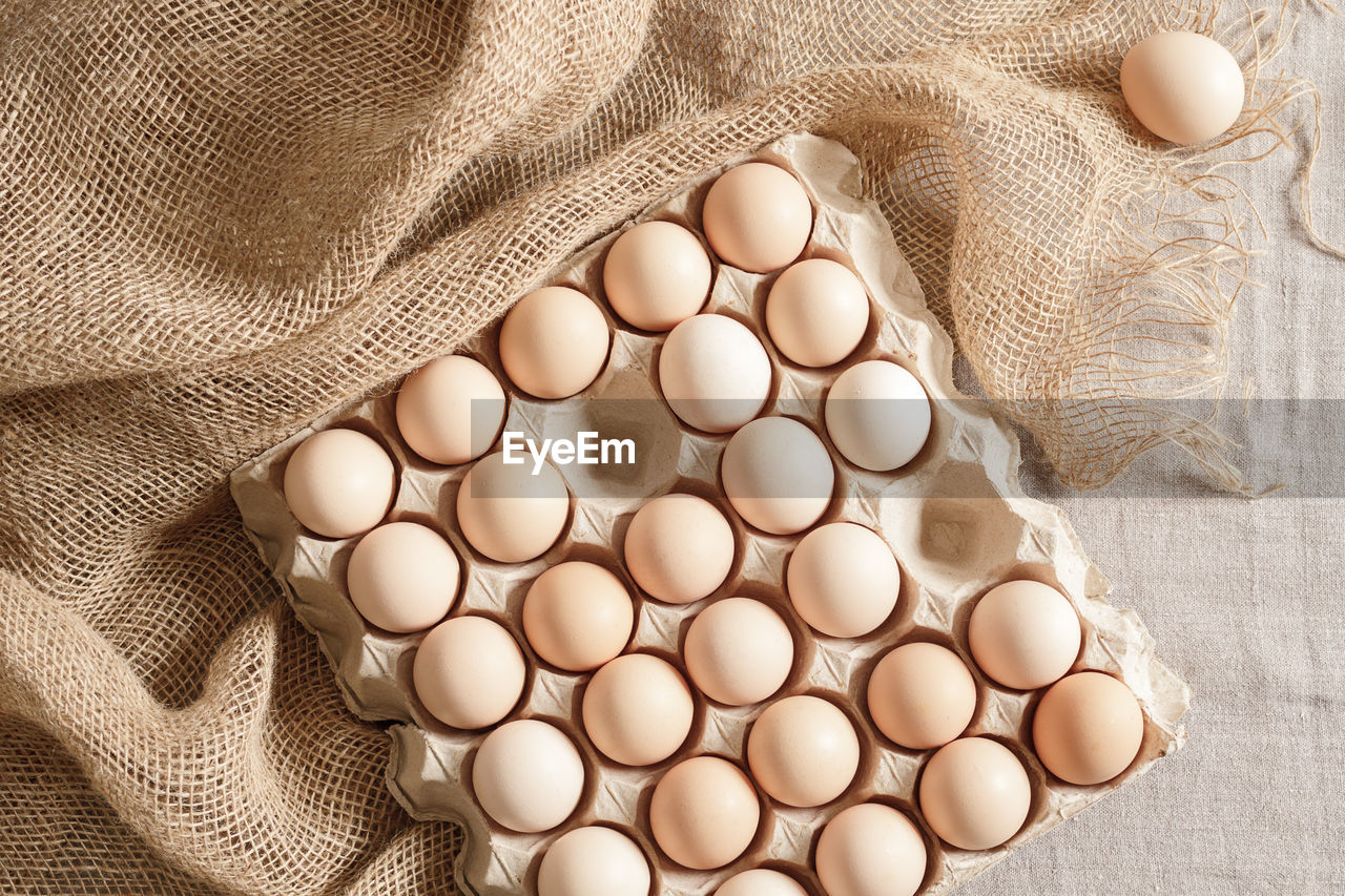 egg, food, food and drink, wellbeing, indoors, freshness, raw food, studio shot, no people, healthy eating, animal egg, brown, organic, textile, protein, high angle view, close-up, directly above, fragility, still life, simplicity, pattern, large group of objects, nature, white