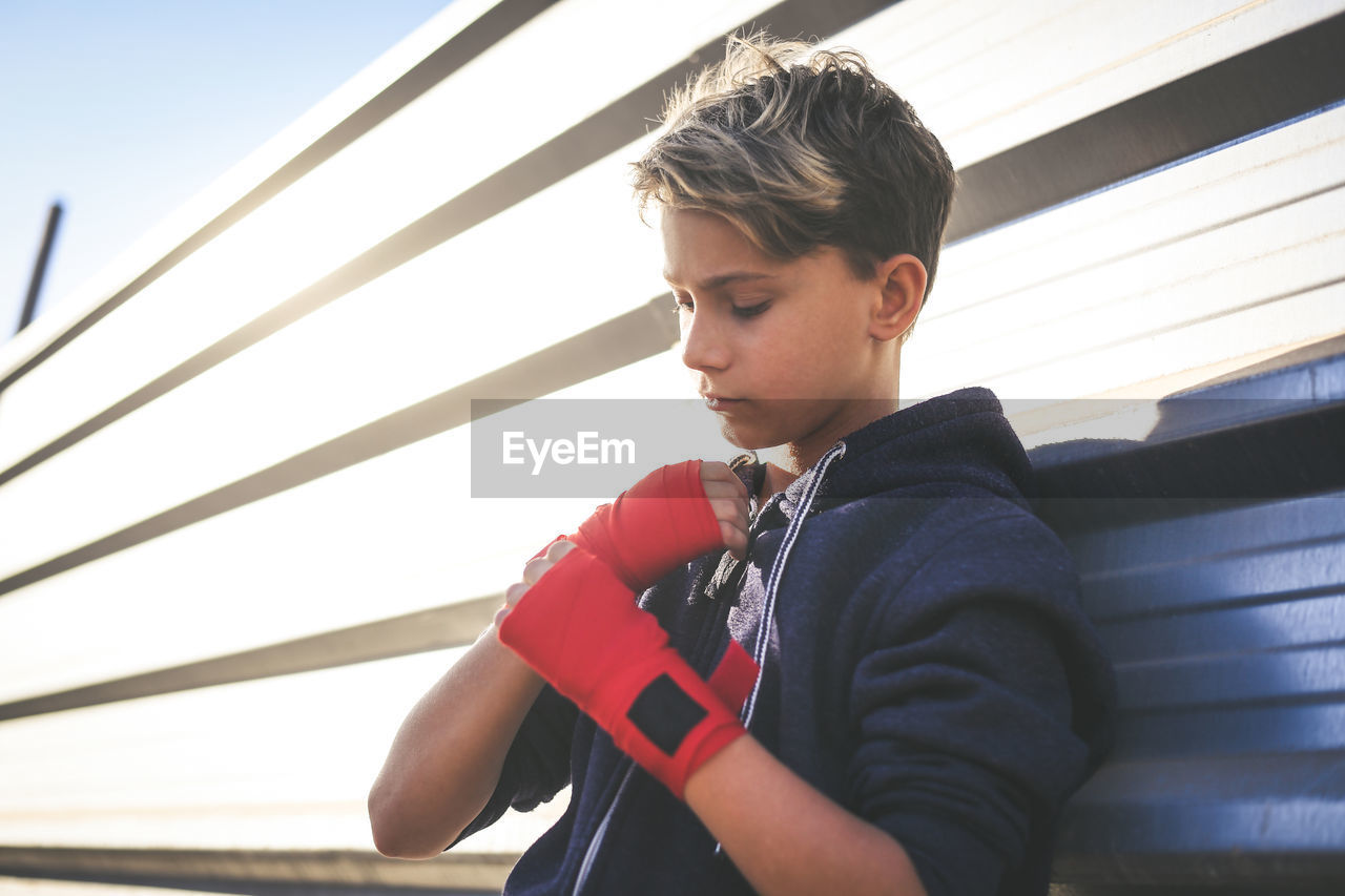 Boy wearing boxing strap while standing outdoors