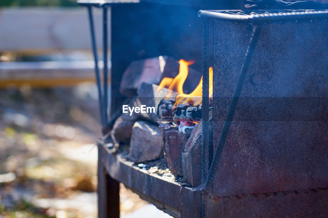 Fire in a rusty vintage grill outdoor with blurred background.