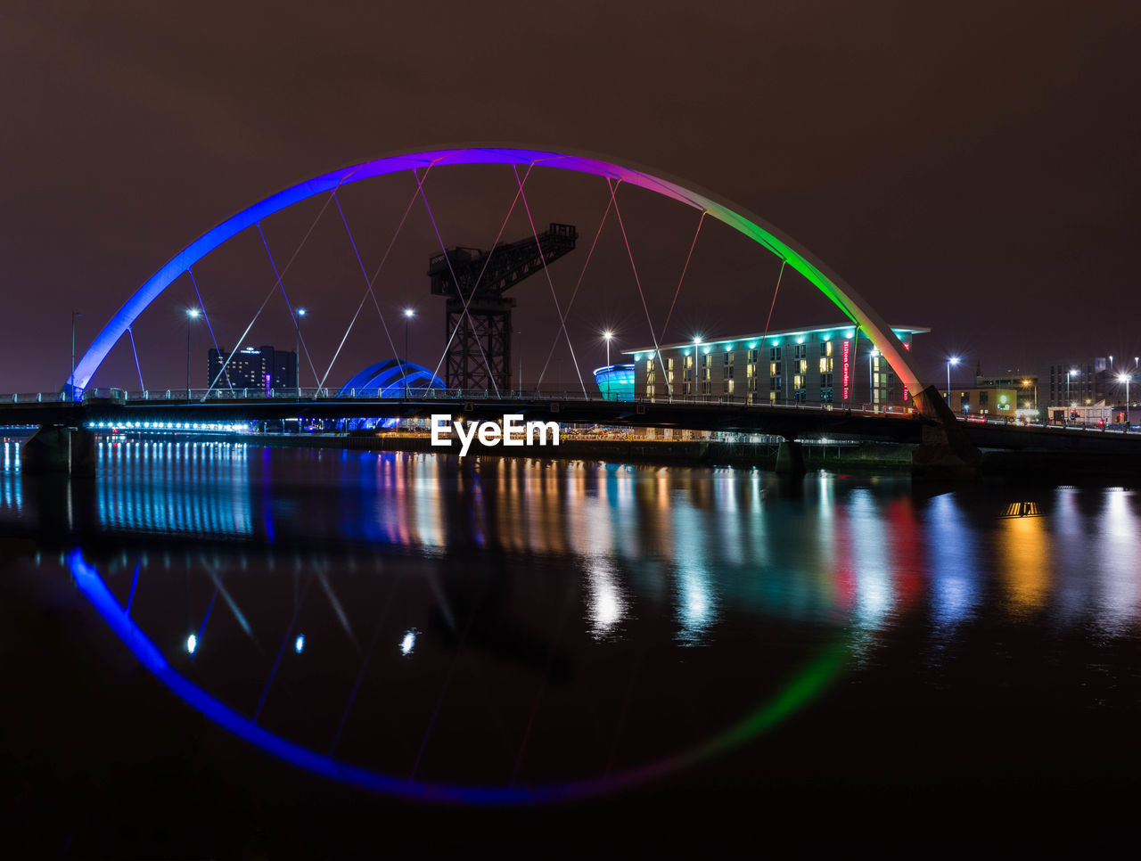 Reflection of bridge and building in water at night