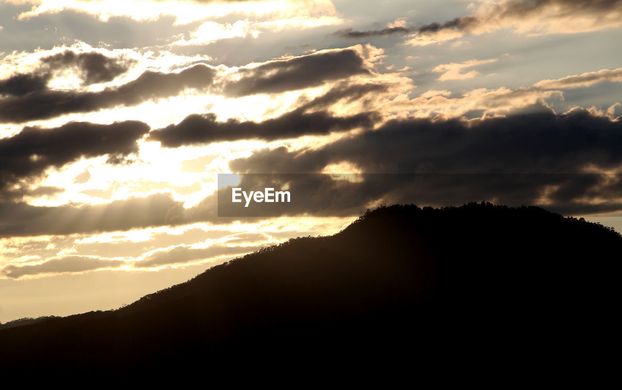 SILHOUETTE MOUNTAINS AGAINST DRAMATIC SKY DURING SUNSET