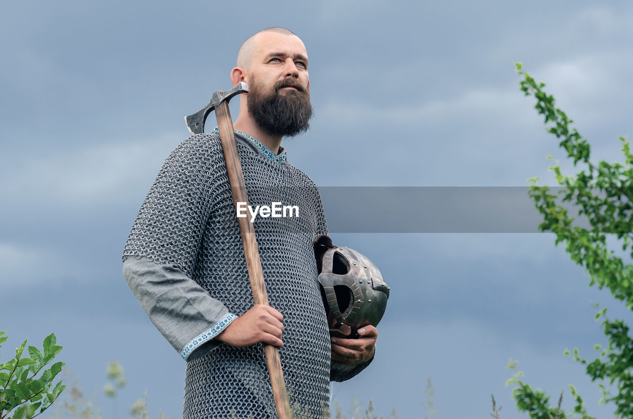 one person, beard, adult, facial hair, men, sky, nature, person, standing, day, holding, plant, looking, clothing, spring, lifestyles, cloud, low angle view, leisure activity, outdoors, copy space, human face, waist up, casual clothing, front view, sports, occupation, mature adult, portrait, looking away