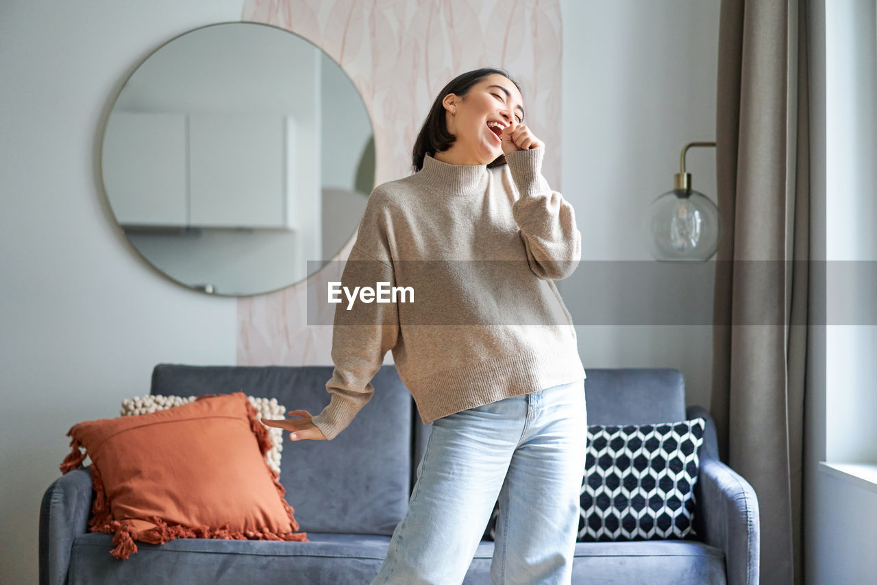 young woman using mobile phone while sitting in living room