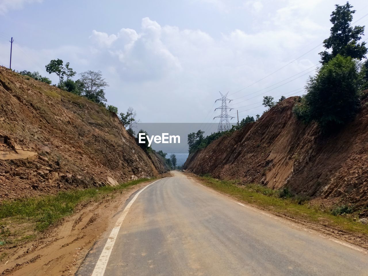 EMPTY ROAD AMIDST TREES AND LANDSCAPE AGAINST SKY