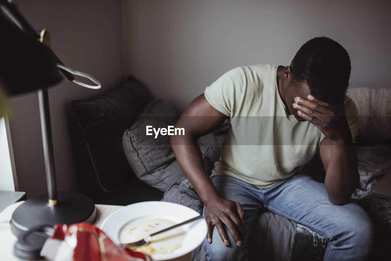 Worried man sitting on bed at home