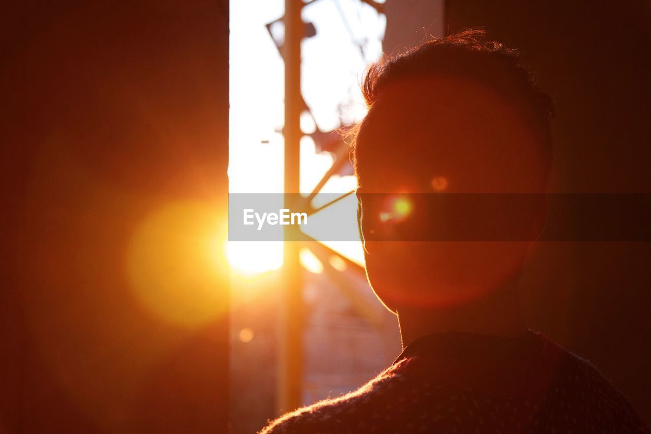 Rear view of man looking out through azar door at sunset