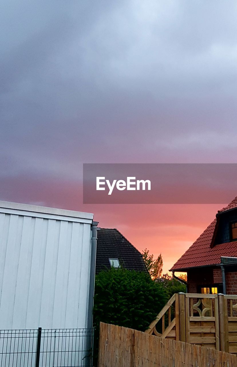 HOUSE BY BUILDING AGAINST SKY