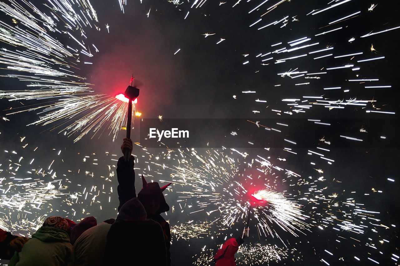 Low angle view of people with fireworks at night