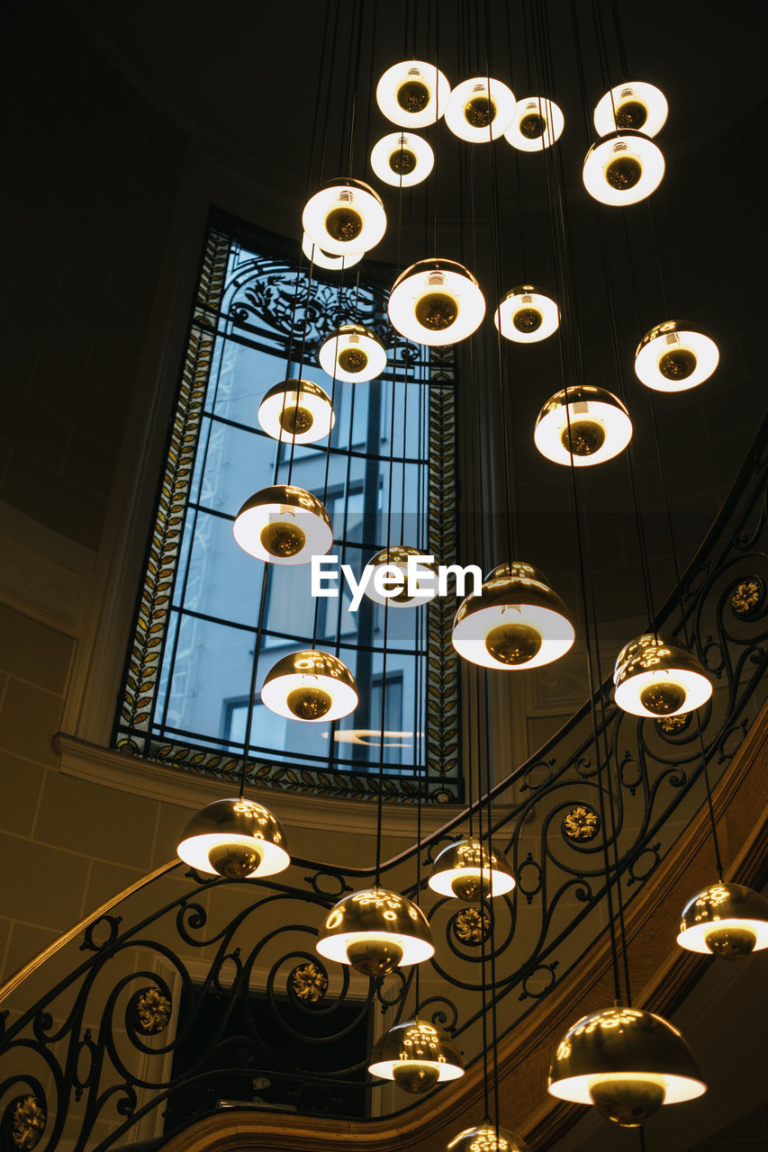 Low angle view of illuminated pendant lights hanging on ceiling in building