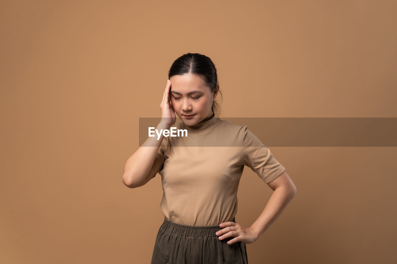 one person, studio shot, adult, women, colored background, indoors, portrait, young adult, standing, photo shoot, copy space, front view, emotion, three quarter length, hairstyle, hand, brown hair, looking at camera, clothing, looking, fashion, brown, sleeve, waist up, female, long hair, smiling