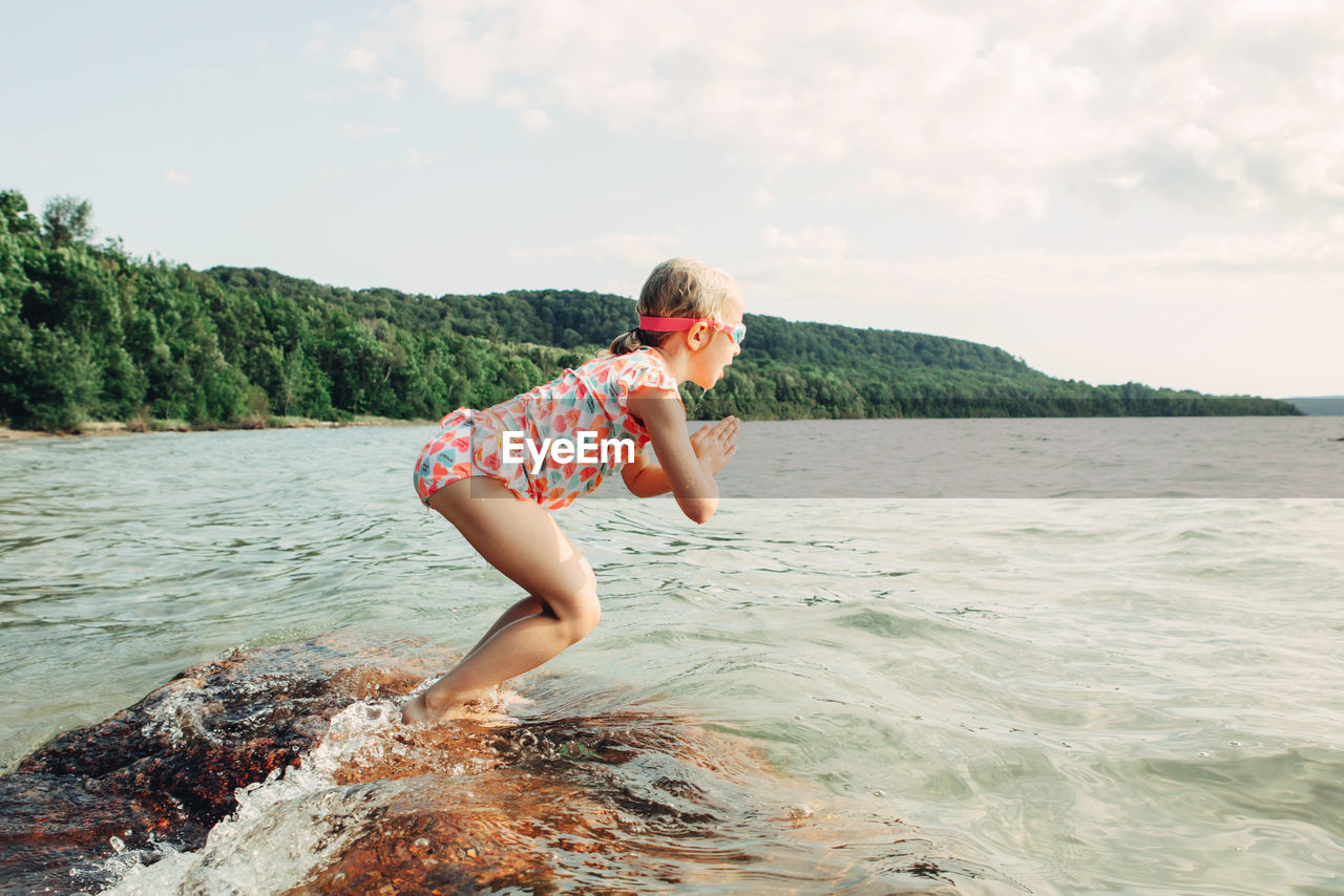 Side view of girl jumping in river