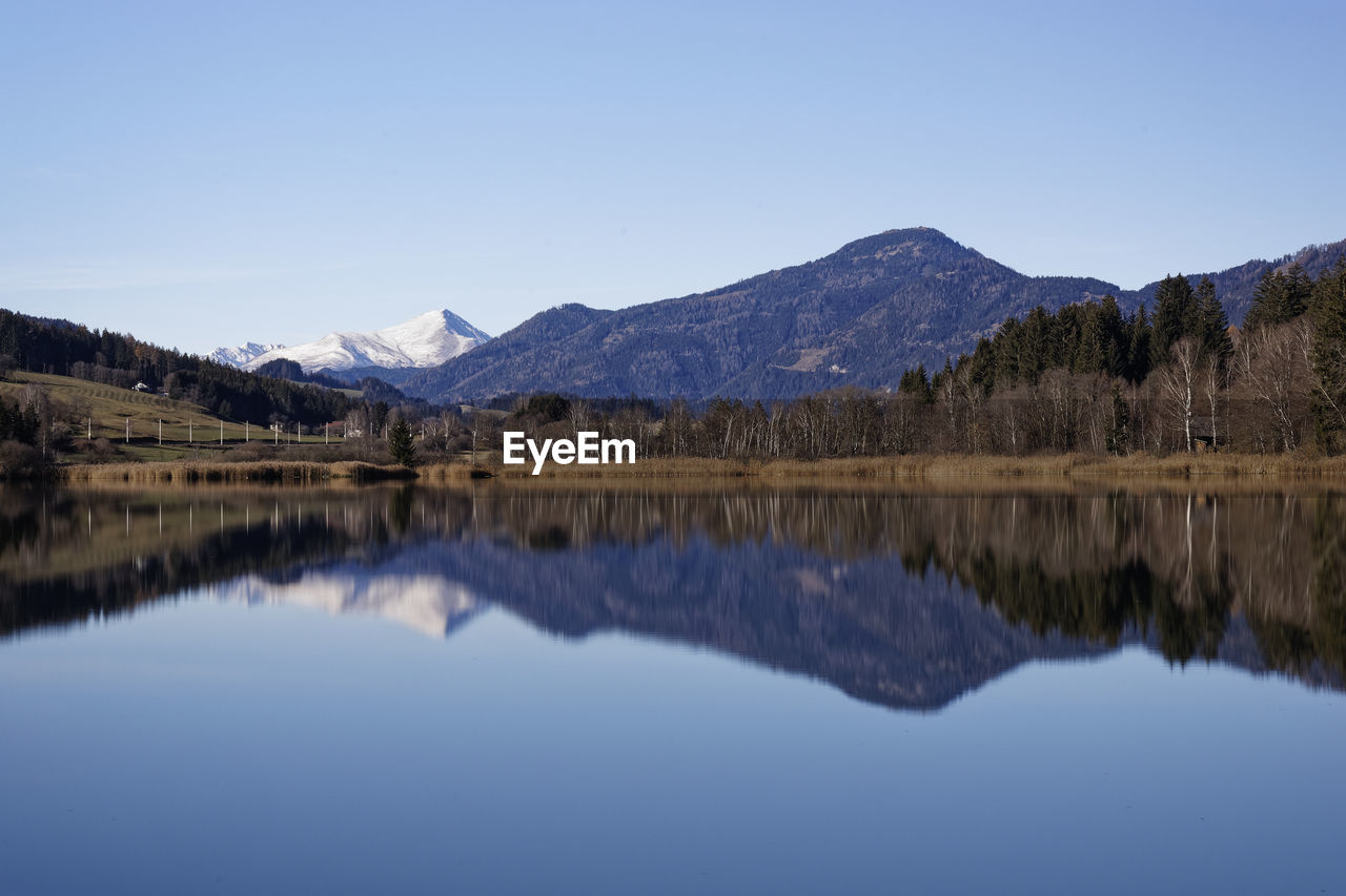 Scenic view of lake and mountains against clear blue sky