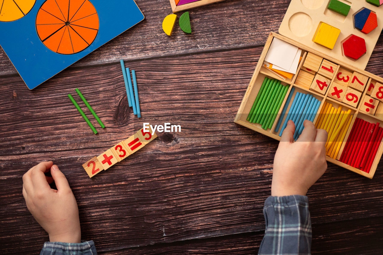 hand, wood, art, one person, directly above, table, high angle view, childhood, indoors, child, creativity, multi colored, leisure activity, holding, adult, men, women, lifestyles, pencil