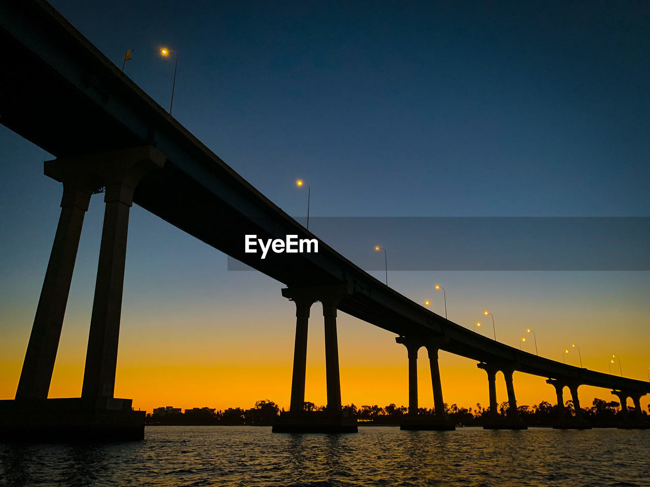 SILHOUETTE BRIDGE OVER RIVER AGAINST ORANGE SKY