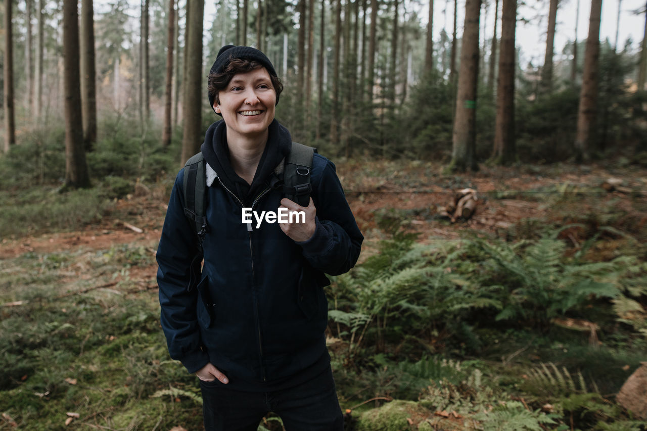 Smiling woman standing against forest