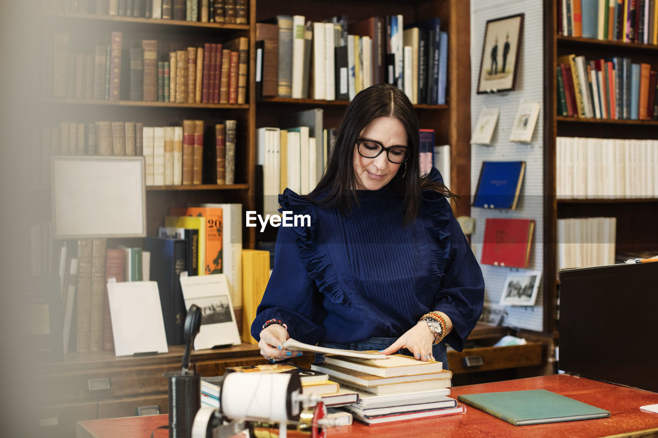 Female librarian looking at books in bookstore