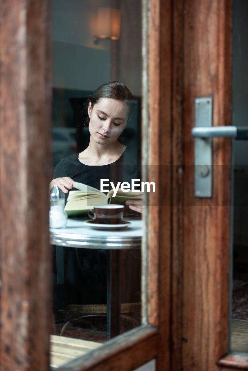 Beautiful woman sitting by table with book