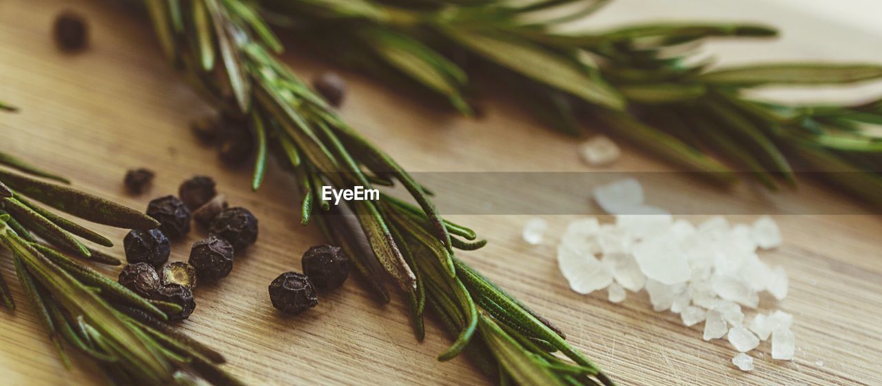 Close-up of rosemary and black peppercorns with salt on table