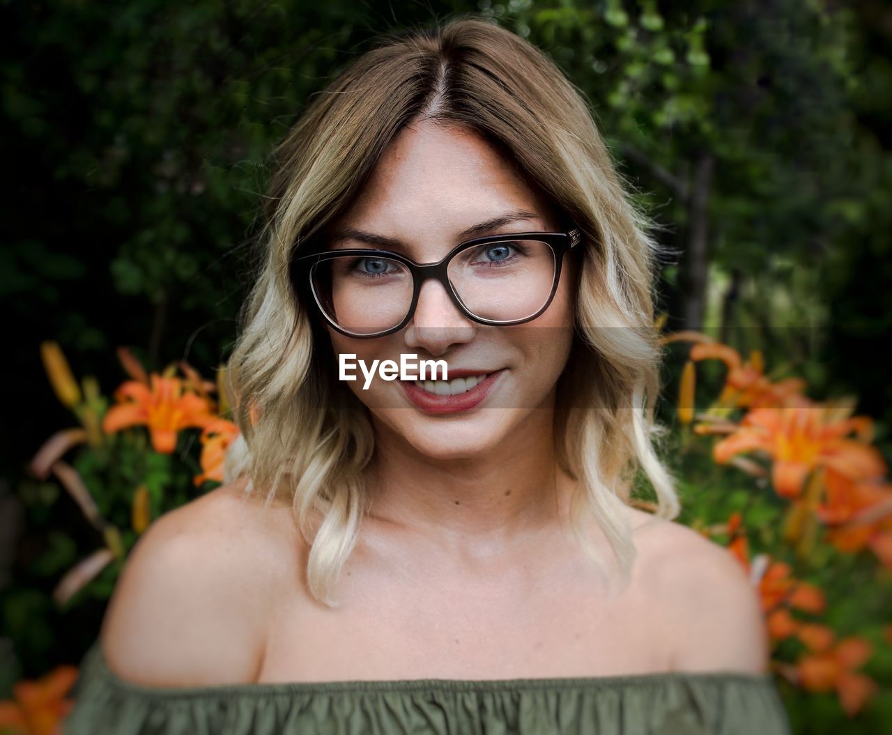 Close-up portrait of young woman wearing eyeglasses against plants