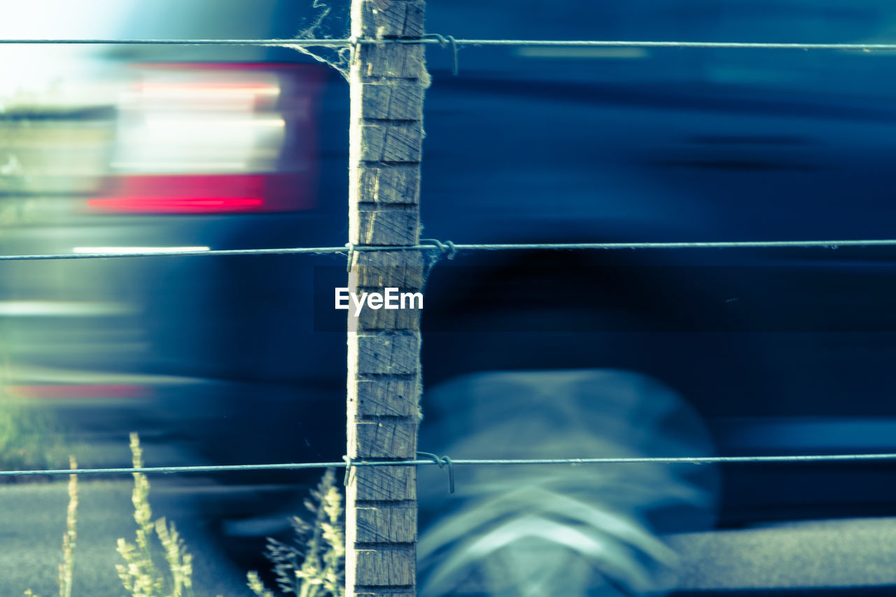 Blurred motion of car seen through fence