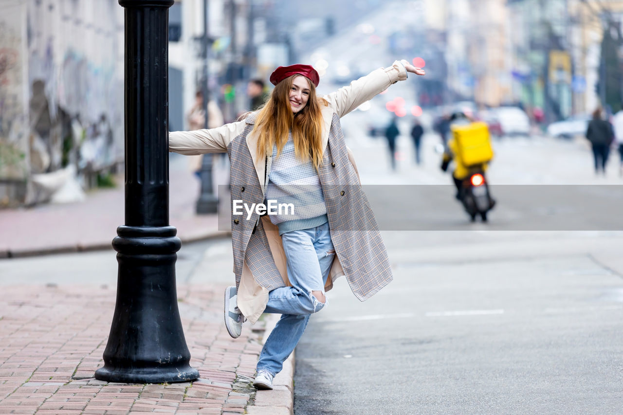 Beautiful girl in a coat, red beret, and jeans walks through the old city.
