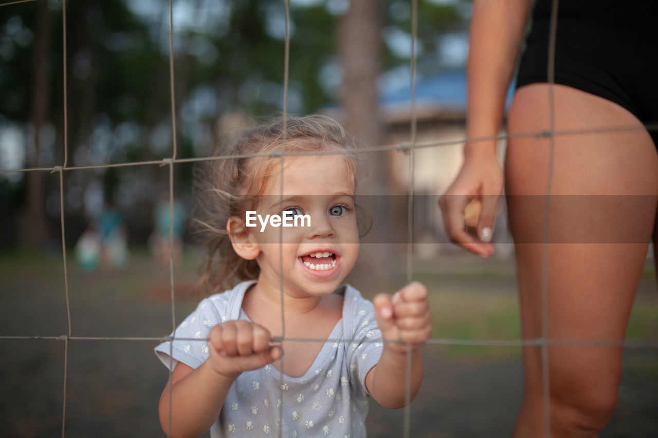 Portrait of cute girl screaming while standing with mother by fence