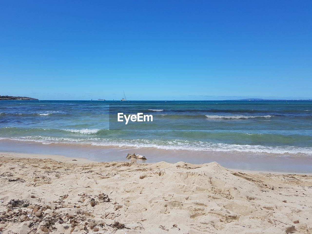 Scenic view of beach against clear blue sky