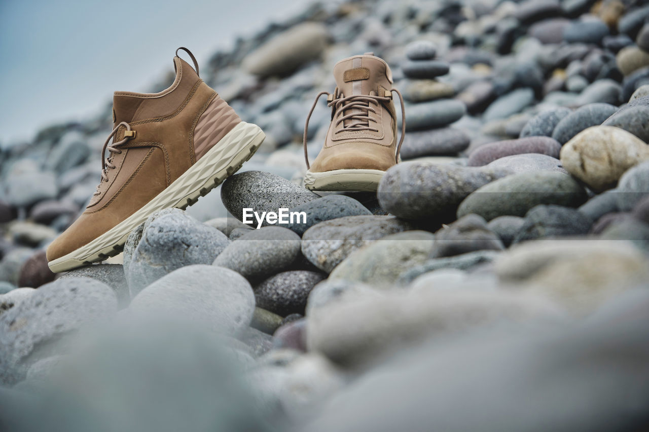 A pair of brown leather waterproof trekking boots on a sea coast. hiking concept.