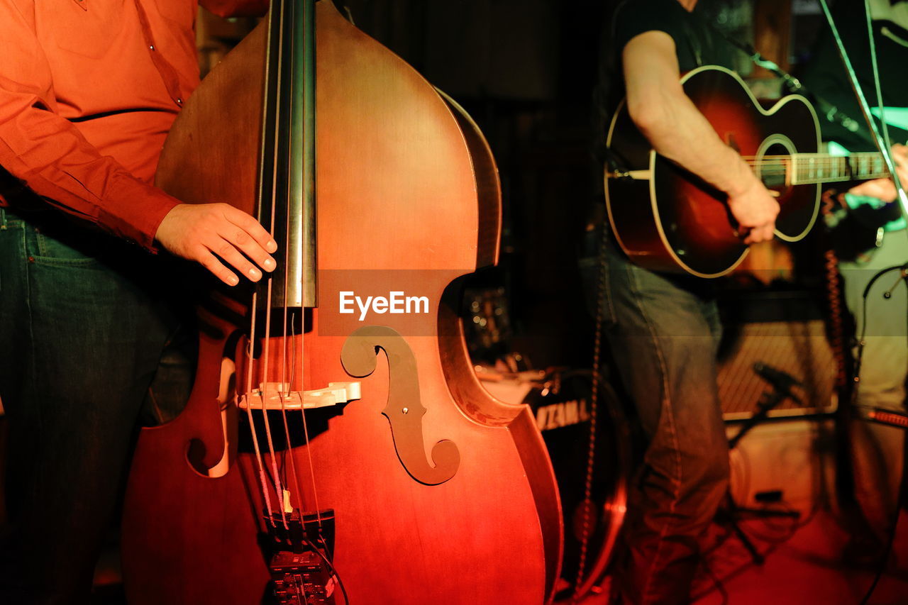 Midsection of man playing guitar and double bass