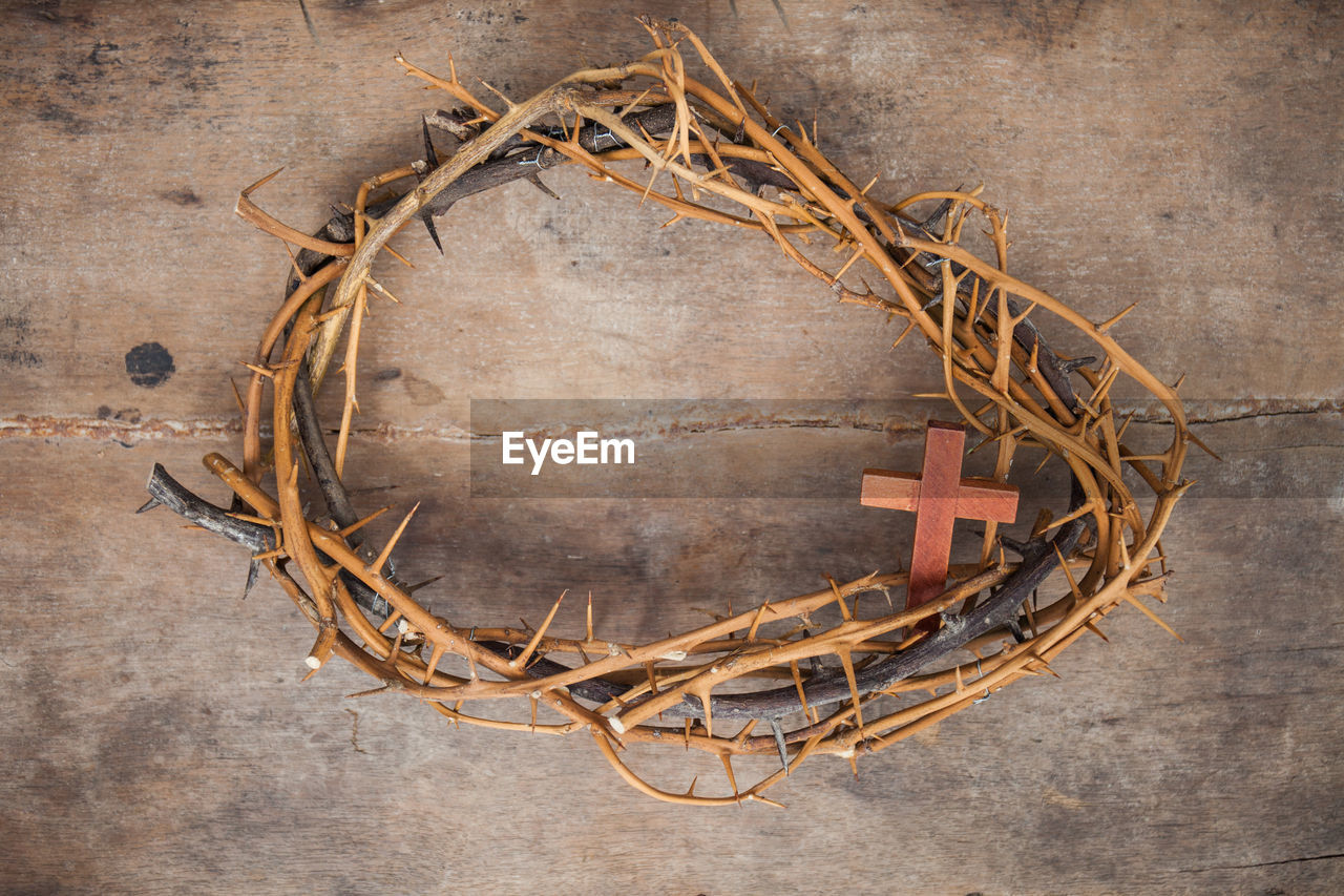Directly above shot of thorn wreath with cross on wooden table