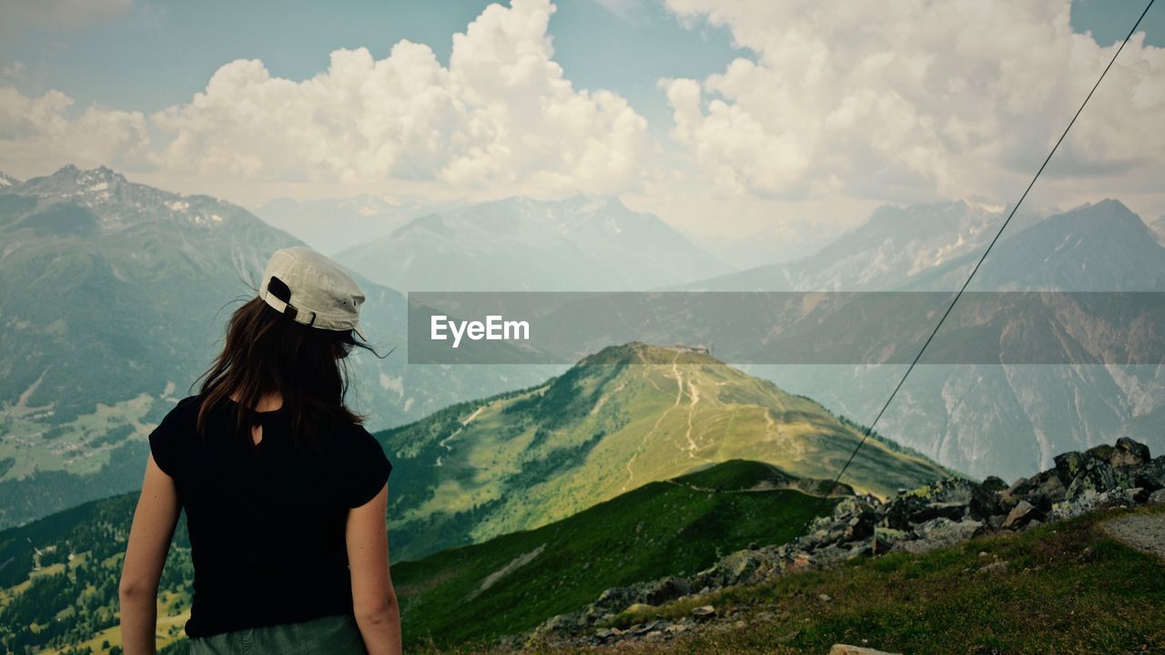 Rear view of woman standing on mountain against sky