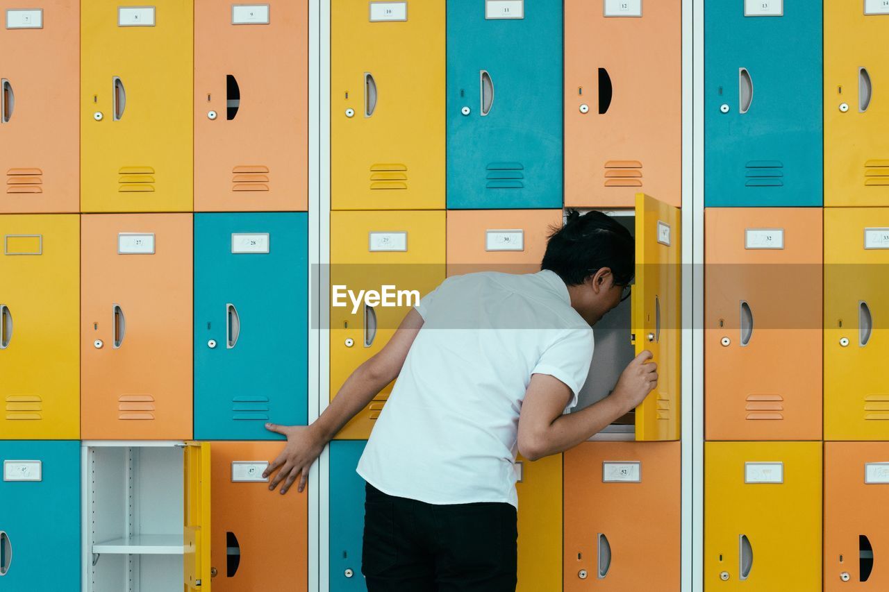 Rear view of young man looking in lockers