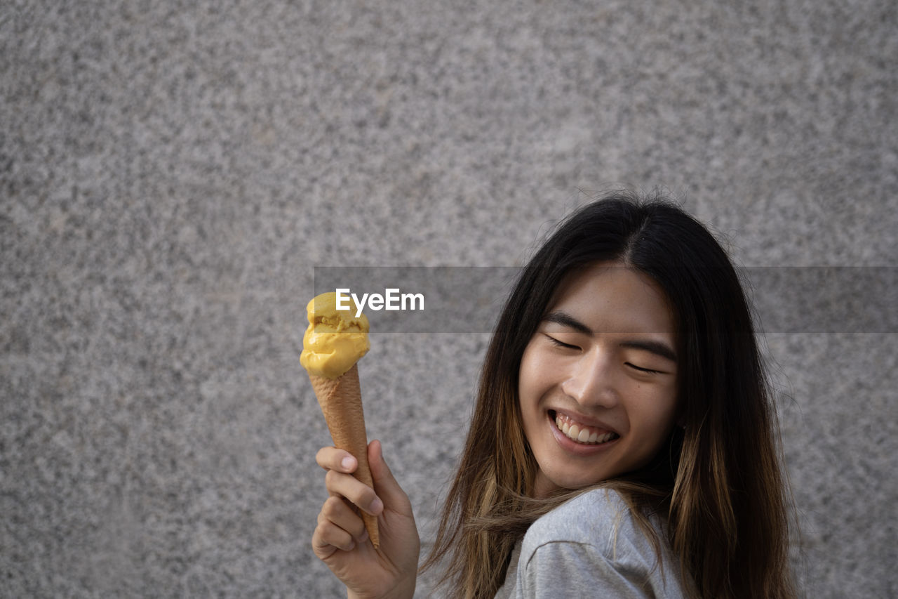 Happy gay male with a yellow ice cream and copy space